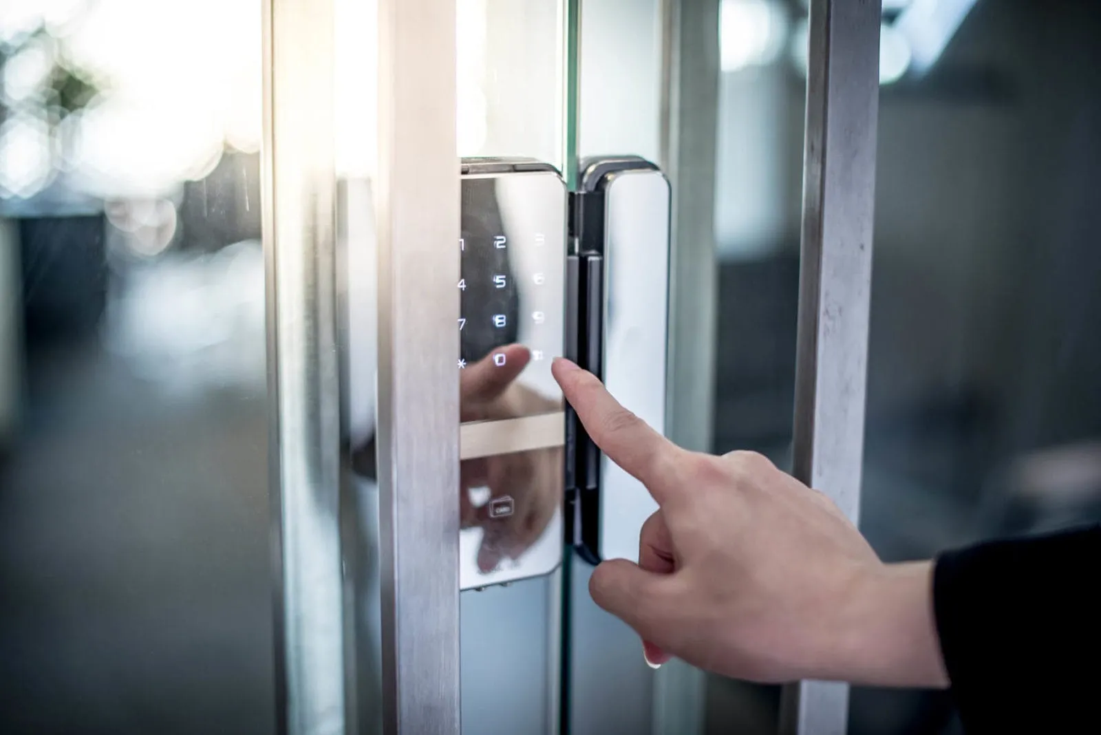 Person using a glass door keypad.